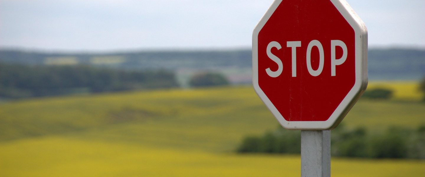Ein Stop-Schild vor einem Rapsfeld.