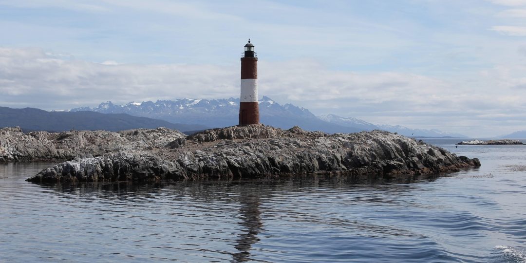 Leuchtturm auf einem Felsen in arktischem Gewässer.