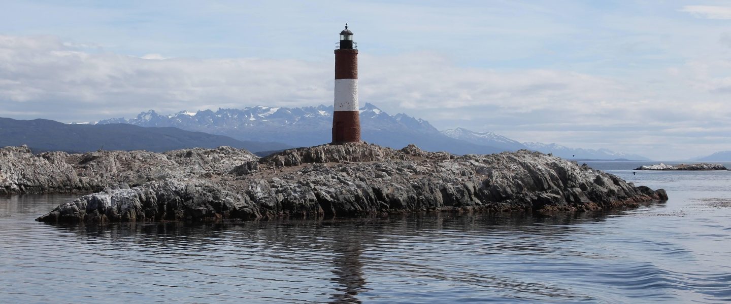 Leuchtturm auf einem Felsen in arktischem Gewässer.